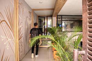 um homem andando por um corredor com plantas em Green Hotel Medellin em Medellín