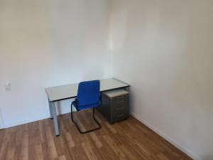 un escritorio con una silla azul junto a un armario en Privatzimmer direkt an der Uniklinik Mainz, en Mainz