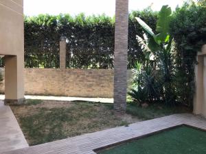 ‘Ezbet el-Insha的住宿－شقه متميزه بالحي التاسع，后院设有砖墙和绿色庭院
