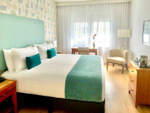 a bedroom with a large bed with blue and green sheets at Avalon Hotel in Miami Beach