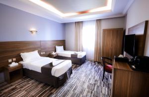 um quarto de hotel com duas camas e uma televisão em فندق زهرة الياسر مكة em Meca