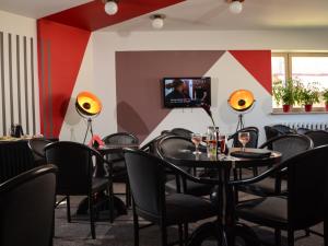 een restaurant met tafels en stoelen en een tv aan de muur bij Mans Nams - self check in hotel in Saldus