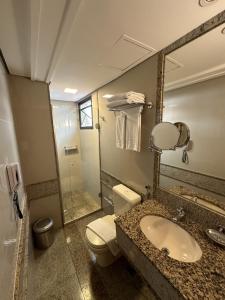 a bathroom with a sink and a toilet and a mirror at Lets Idea Brasilia Hotel - Flat Particular in Brasilia