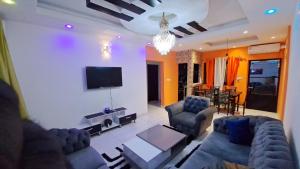 sala de estar con 2 sofás y TV de pantalla plana en Residence GermanoTech, Bonamoussadi,Logbessou appartement meublé 2ch,1salon eau chaude,Wifi,parking,virgile,menagere,canalsat, en Douala