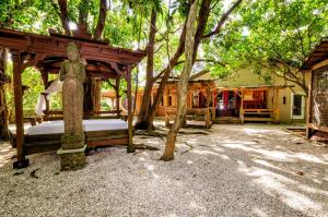 霍姆斯泰德的住宿－Exotic Sukiya Tiny House Japanese Balinese Gardens，坐在树下床边的人的雕像