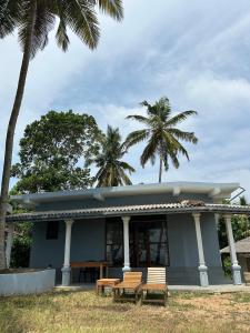 a blue house with two chairs and palm trees at pemuyan mirissa70 in Mirissa