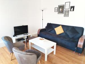 uma sala de estar com um sofá e cadeiras e uma televisão em Cosy central London Apartment, EC1V em Londres