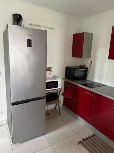 a kitchen with a refrigerator and red cabinets at Kama in Sainte-Luce