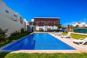 uma piscina com duas espreguiçadeiras e uma casa em Coastal Comfort Haven em Nuevo Vallarta