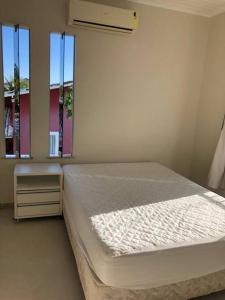una camera da letto con un letto e due finestre di CASA DE PRAIA NO CONDOMÍNIO PARAÍSO, GUARAJUBA a Camassari