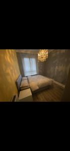 a bedroom with a bed with a window and a chandelier at Town centre apartment in Motherwell