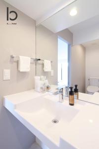 un bagno bianco con due lavandini e uno specchio di bHOTEL Heiwaoodori 401 - Brand New Apt Famous Hiroshima Dori 6ppl a Hiroshima