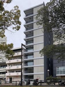 un edificio alto con una motocicleta estacionada frente a él en bHOTEL Heiwaoodori 102 - Beautiful New 1BR Apartment for 6 ppl, en Hiroshima