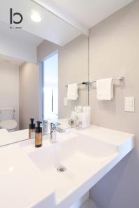 Baño blanco con lavabo y espejo en bHOTEL Heiwaoodori 102 - Beautiful New 1BR Apartment for 6 ppl, en Hiroshima