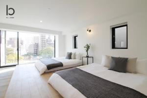 two beds in a white room with a large window at b hotel Heiwaodori 501 - Huge Apt Famous Hiroshima Dori For 6ppl in Hiroshima