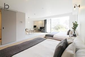 sala de estar con 2 camas y sofá en bHOTEL Heiwaoodori 501 - Huge Apt Famous Hiroshima Dori For 6ppl, en Hiroshima