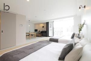 1 dormitorio blanco con 2 camas y comedor en bHOTEL Heiwaoodori 901 - New Apt in Famous Hiroshima Dori For 6p, en Hiroshima