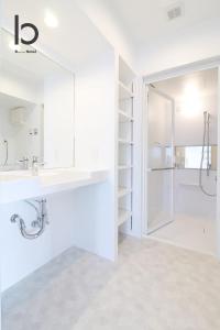 La salle de bains blanche est pourvue d'un lavabo et d'une douche. dans l'établissement bHOTEL Heiwaoodori 901 - New Apt in Famous Hiroshima Dori For 6p, à Hiroshima