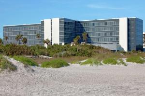 Hilton Cocoa Beach Oceanfront في كوكاو بيتش: مبنى على الشاطئ بجوار شاطئ رملي