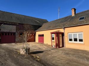 eine Garage mit einer roten Tür und einem Gebäude in der Unterkunft Maison de famille in Pré-en-Pail