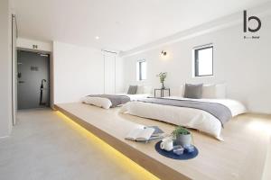 広島市にあるb hotel Heiwaodori 602 - Huge Apt in Famous Hiroshima Dori for 6pのベッド2台とテーブルのある白い寝室