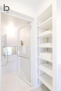a white bathroom with white shelves and a shower at bHOTEL Heiwaoodori - Huge Apt in Famous Hiroshima Dori for 6p in Hiroshima
