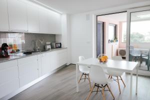 una cucina bianca con tavolo e sedie bianchi di Spacious Seaside apartment A - Faraway a Lagoa