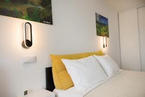 1 dormitorio con cama blanca y almohada amarilla en Spacious Seaside apartment A - Faraway, en Lagoa