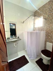 a white bathroom with a toilet and a sink at Casa em Natal /Extremoz - RN in Extremóz