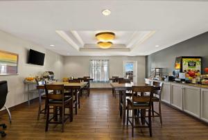 a dining room with tables and chairs and a kitchen at MainStay Suites Houma in Houma