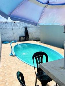 einen Pool mit einem Tisch, Stühlen und einem Sonnenschirm in der Unterkunft Casa em Natal /Extremoz - RN in Extremóz