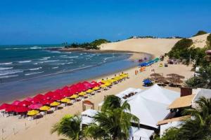 a beach with colorful umbrellas and the ocean at Casa no Litoral Norte de Natal in Extremóz