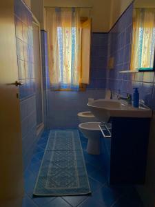 bagno piastrellato blu con lavandino e servizi igienici di Pinníga’s House Mega appartamento vista mare a Santa Maria Navarrese