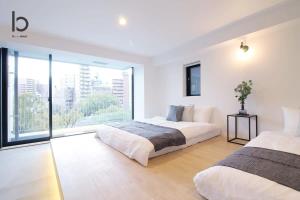 a bedroom with two beds and a large window at bHOTEL Heiwaoodori 201 - New Apt in Famous Hiroshima Dori Max 6p in Hiroshima