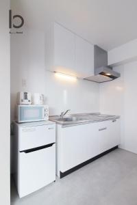 a white kitchen with a sink and a microwave at bHOTEL Heiwaoodori - New Apt in Famous Hiroshima Dori Max 6p in Hiroshima