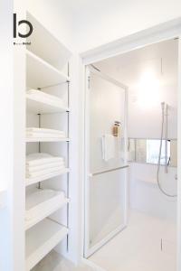 a bathroom with white shelves and a shower at bHOTEL Heiwaoodori 201 - New Apt in Famous Hiroshima Dori Max 6p in Hiroshima