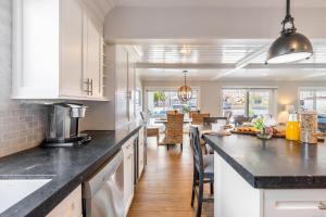 a kitchen with white cabinets and black counter tops at Ocean Breeze I by AvantStay Steps to the Beach in Newport Beach