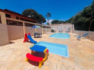 a pool with chairs and a table and an umbrella at Pousada Terraço in Socorro