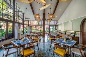 un restaurant avec des tables, des chaises et des fenêtres dans l'établissement Mandrem Beach Resort, a member of Radisson Individuals Retreat, à Mandrem