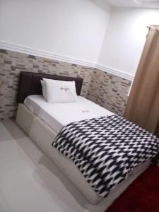 a small bed with a black and white blanket on it at Cheerful and peaceful 4-bedrooms house in Koforidua