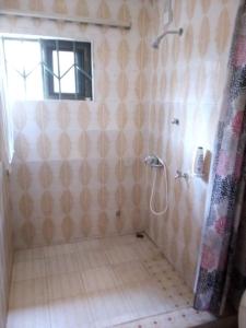 a bathroom with a shower and a tiled floor at Cheerful and peaceful 4-bedrooms house in Koforidua