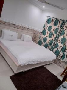 1 dormitorio con cama blanca y cortina en Cheerful and peaceful 4-bedrooms house, en Koforidua