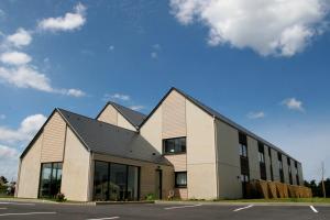 un gran edificio blanco con techo negro en Gold Beach Hotel & RESIDENCE, en Asnelles