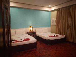 a bedroom with two beds with red flowers on them at Legacy Mansion + coffee bar in Iloilo City