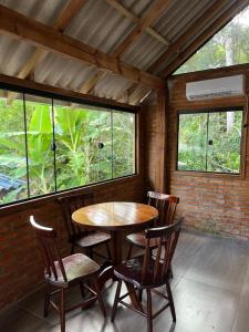 a table and chairs in a room with windows at Pousada Maikai Garden in Porto Belo