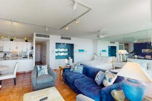 a living room with a blue couch and a kitchen at Galvestonian 710 in Galveston