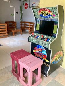 una máquina de videojuegos con un banco rosa al lado en Hostal Republic, en Mérida