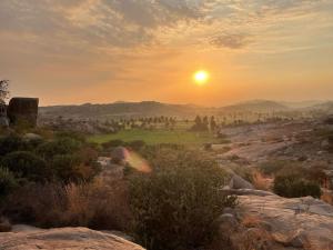 een zonsondergang boven een golfbaan met zonsondergang bij Thilak Home Stay in Hampi