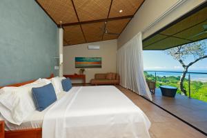 a bedroom with a bed and a view of the ocean at Hotel Three Sixty - Adults Only in Ojochal