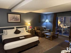 a hotel room with a bed and a chair at Divya Sutra Plaza and Conference Centre, Vernon, BC in Vernon